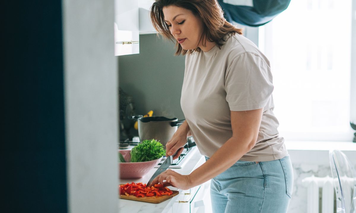 Kvinde står i køkkenet og laver mad.
