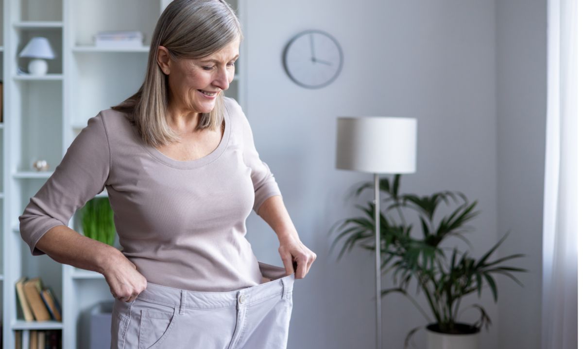 Glad ældre kvinde iført sine for store bukser, som passede inden hun fik lavet fedmeoperation ved Aleris.