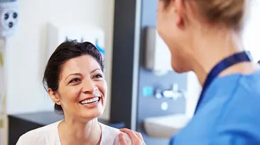 Patient og læge står og smiler til hinanden.