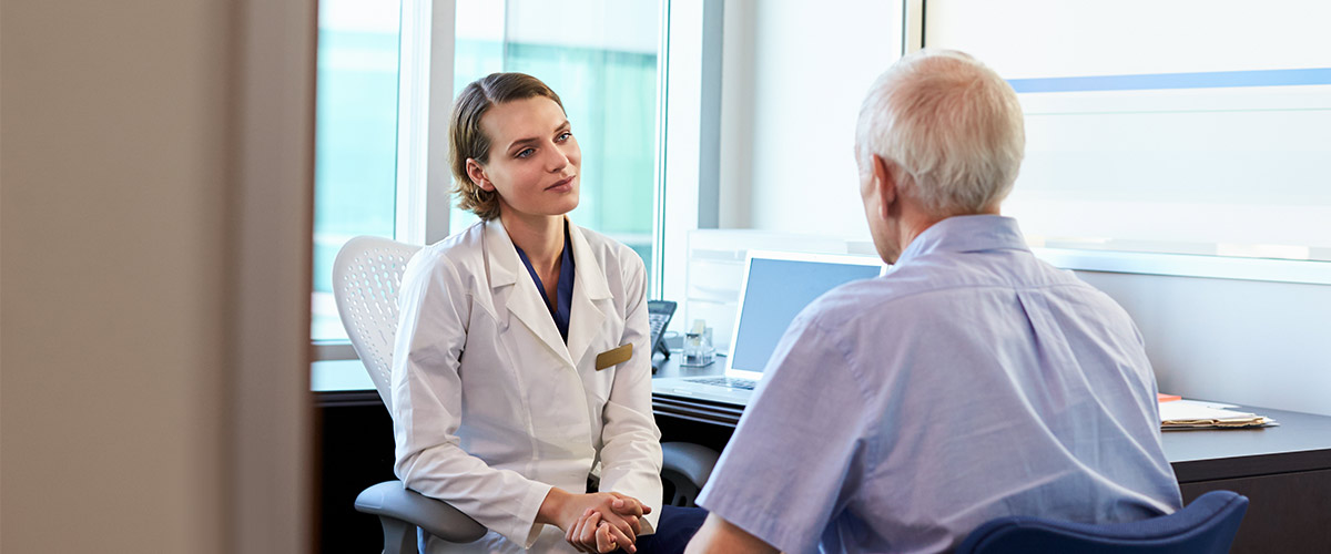 Patient og læge sidder under en konsultation.