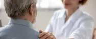 Læge holder på skulderen af en patient,