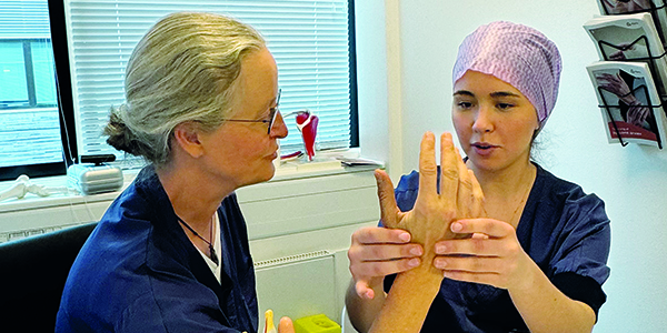 En medicinstuderende undersøger en hånd.