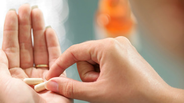 Kvinde skal til at indtage to piller som ligger klar i hendes hånd.