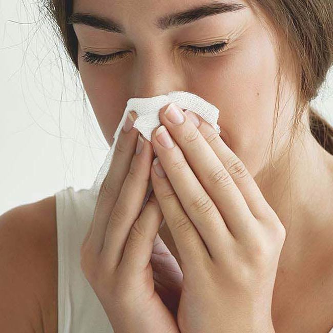 En kvinde med allergi pudser sin næse.