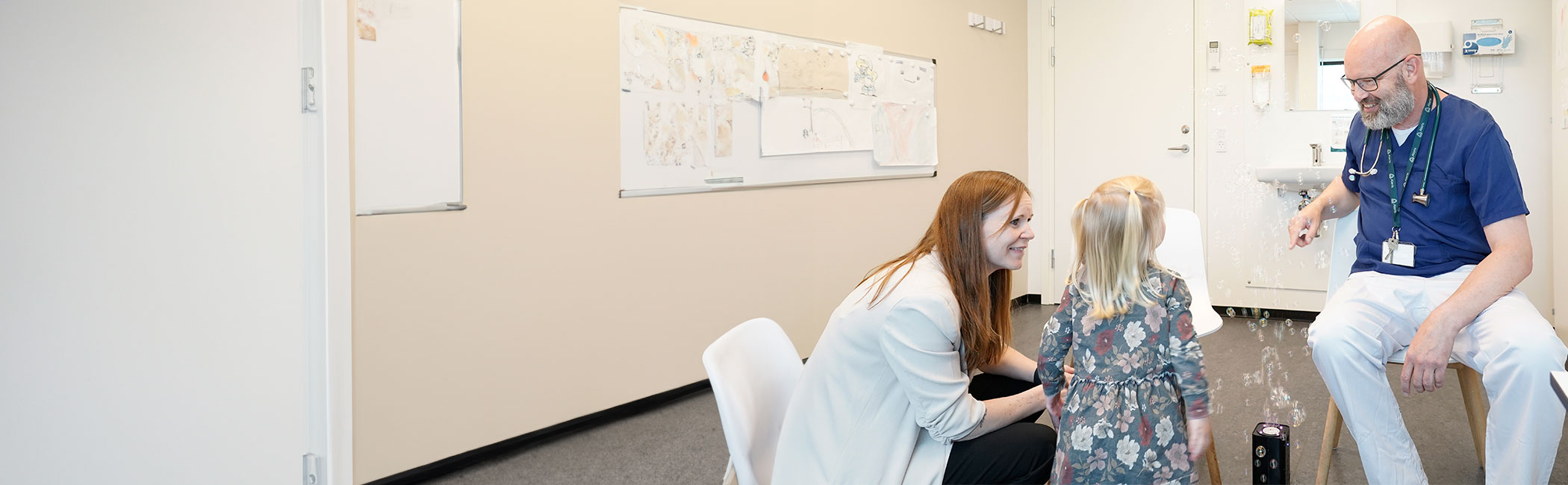 Børnelæge sammen med forældre og barn i en konsultation.