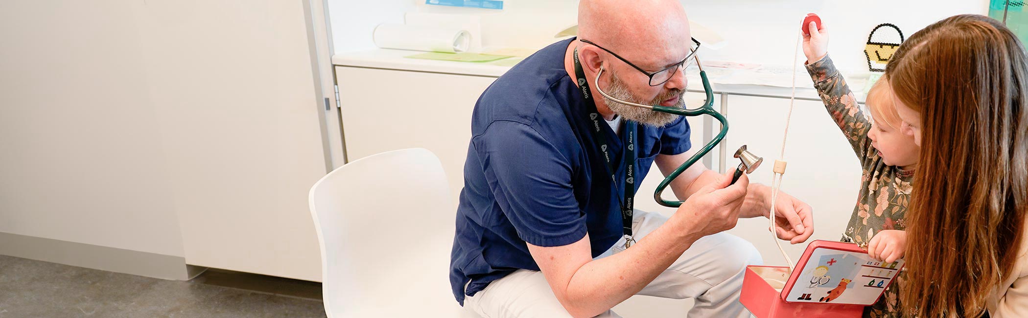 Børnelæge taler med mor og barn i konsultation omkring mavesmerter.