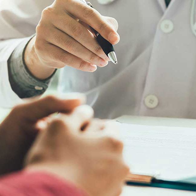 Læge skriver patient oplysninger ned under konsultation.