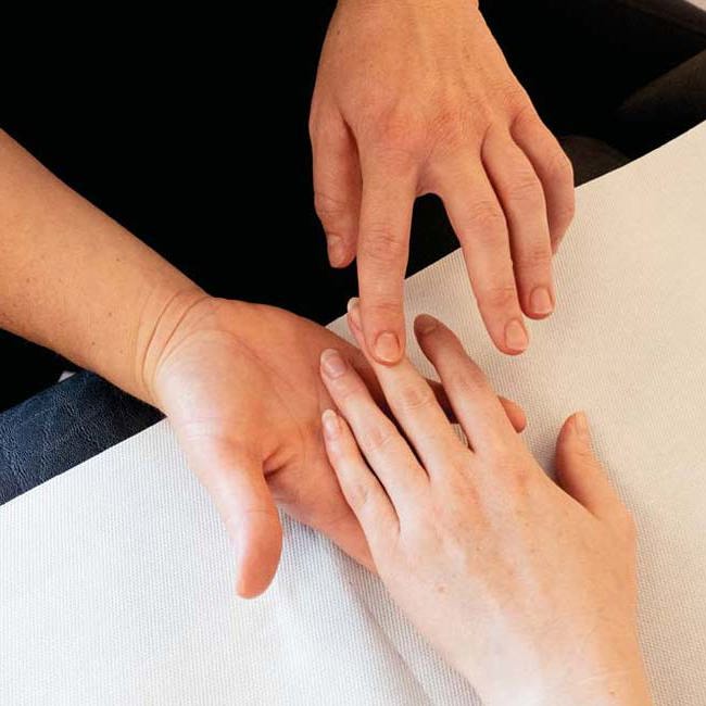 Fysioterapeut fra Aleris mærker patients mobilitet i hænder og fingre.