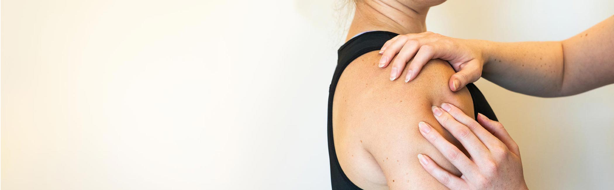 Fysioterapeut masserer patient på skulderen.