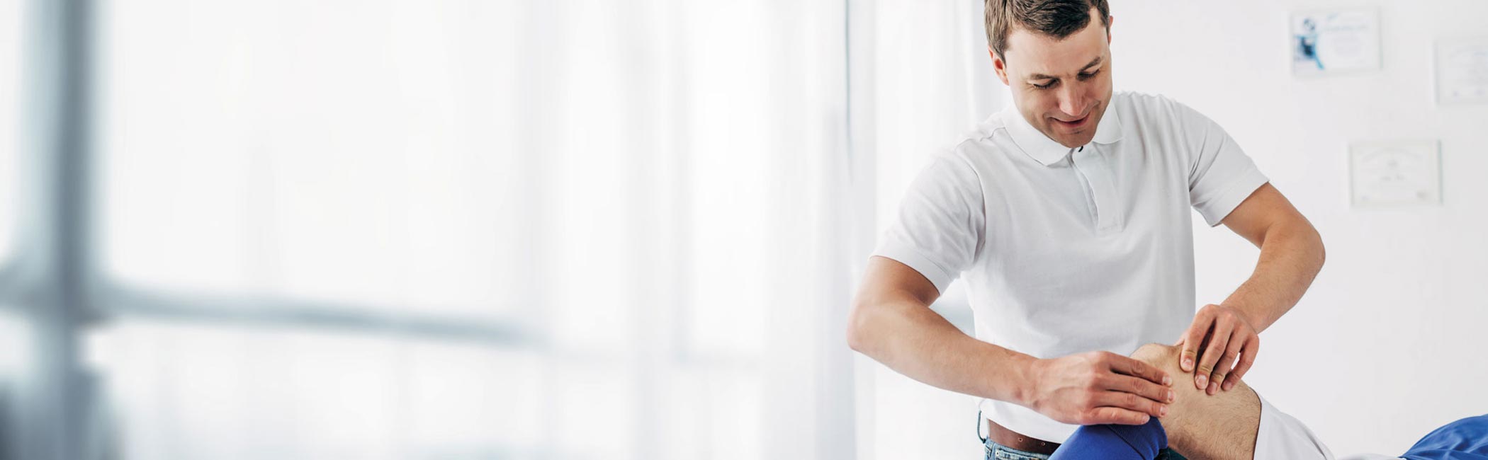 Fysioterapeut masserer patient på knæet.