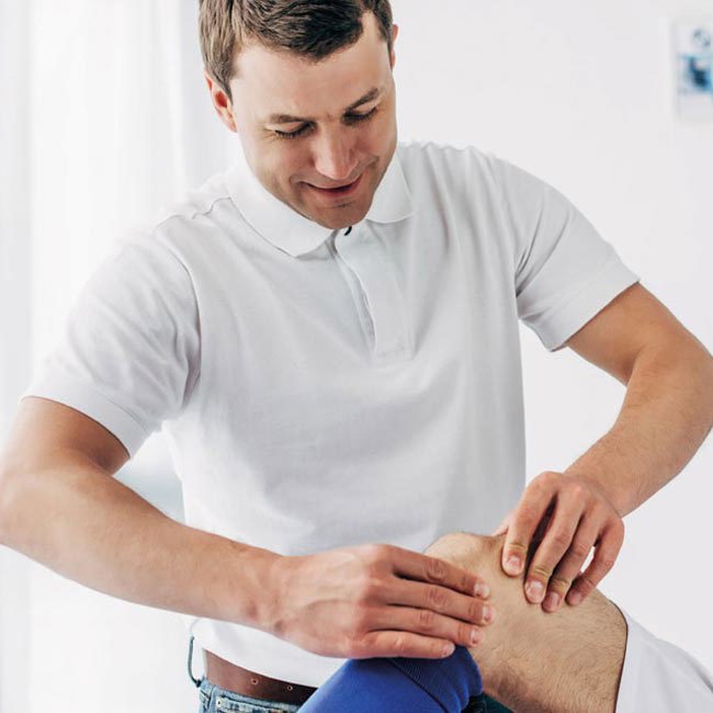 Fysioterapeut masserer patient på knæet.