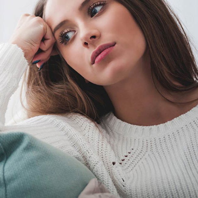 Kvinde sidder tænkende og kigger.