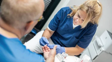 Sygeplejerske måler blodsukker under en helbredsundersøgelse hos Aleris.