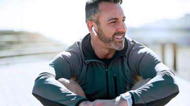 Glad mand sidder i naturen og lytter til musik.