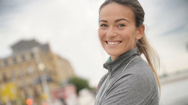 Kvinde i træningstøj smiler til kameraet.