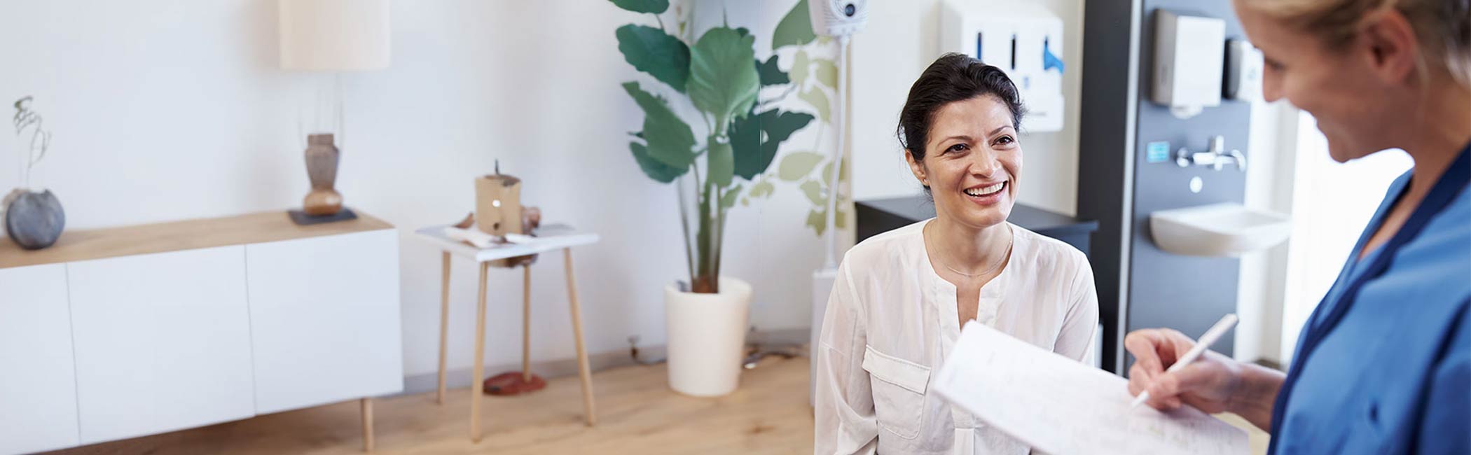 Læge og patient sidder og smiler.