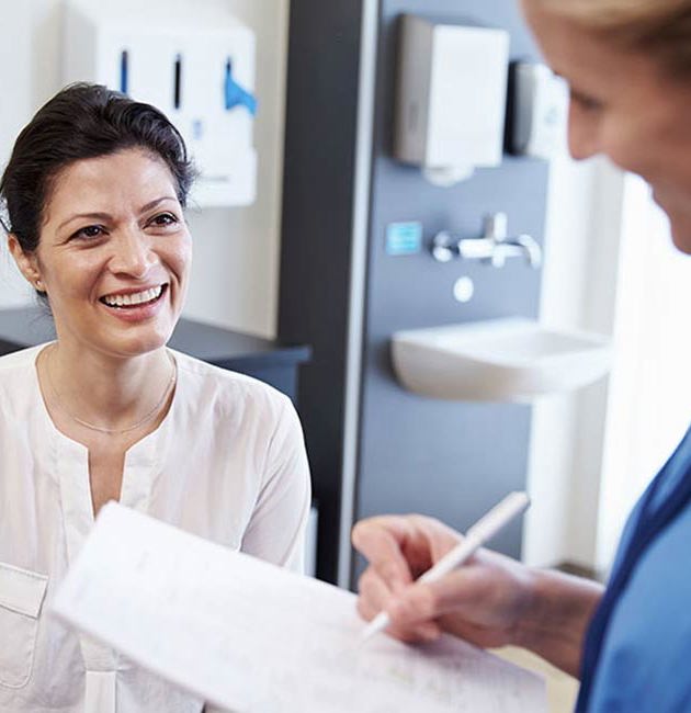 Læge og patient sidder og smiler.