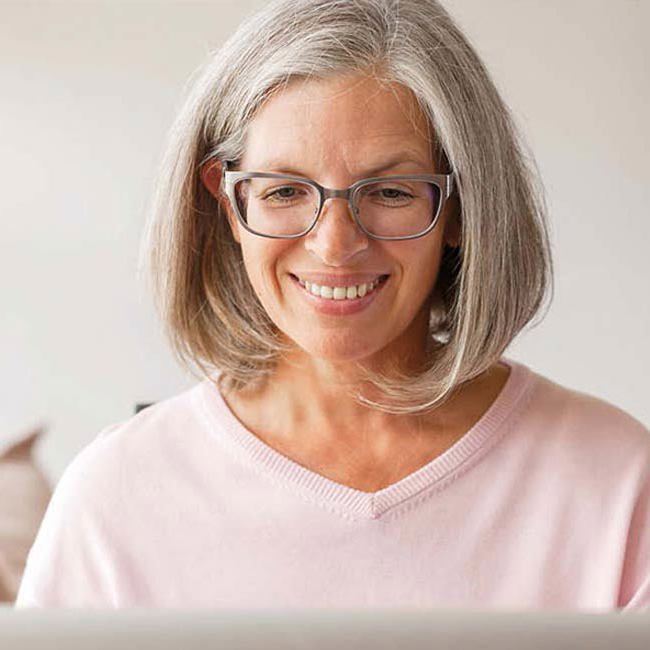 Kvinde sidder smilende ved sin computer.