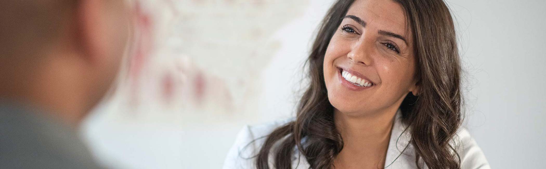 En kvindelig diætist sidder smilende og kigger på en patient.