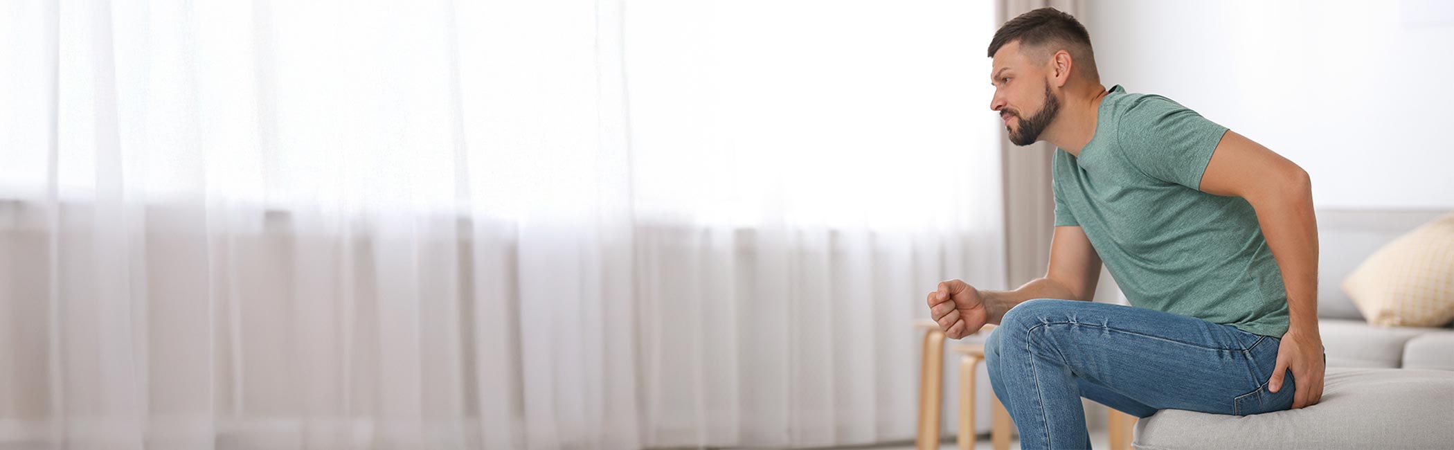 Mand sidder med smerter i endetarmen inden hæmoridebehandling.