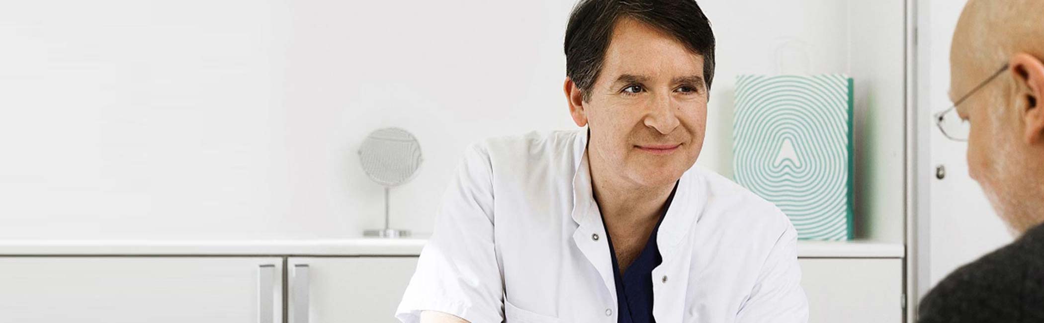 Mandlige neurolog sidder og snakker med en patient.