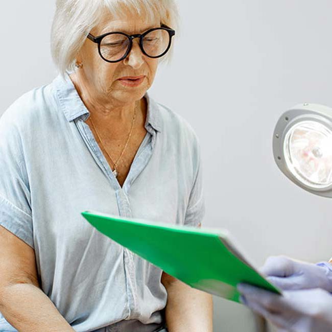 Læge vejleder ældre kvinde efter halscyste.