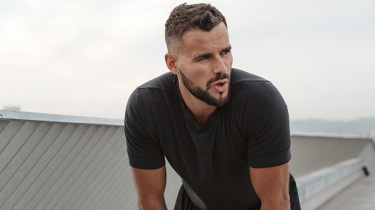 Mand står stille let foroverbøjet og prøver at få vejret.