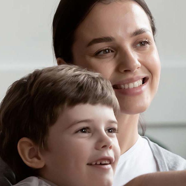 En mor og et barn smiler ved et besøg hos en børneortopædkirurg.