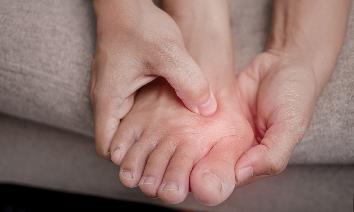 Person holder om sin storetå, der gør ondt.