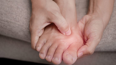 Person holder om sin storetå, der gør ondt.