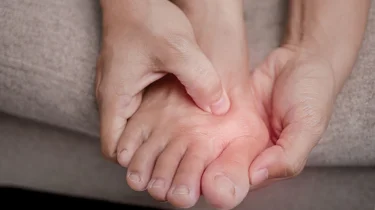 Person holder om sin storetå, der gør ondt.