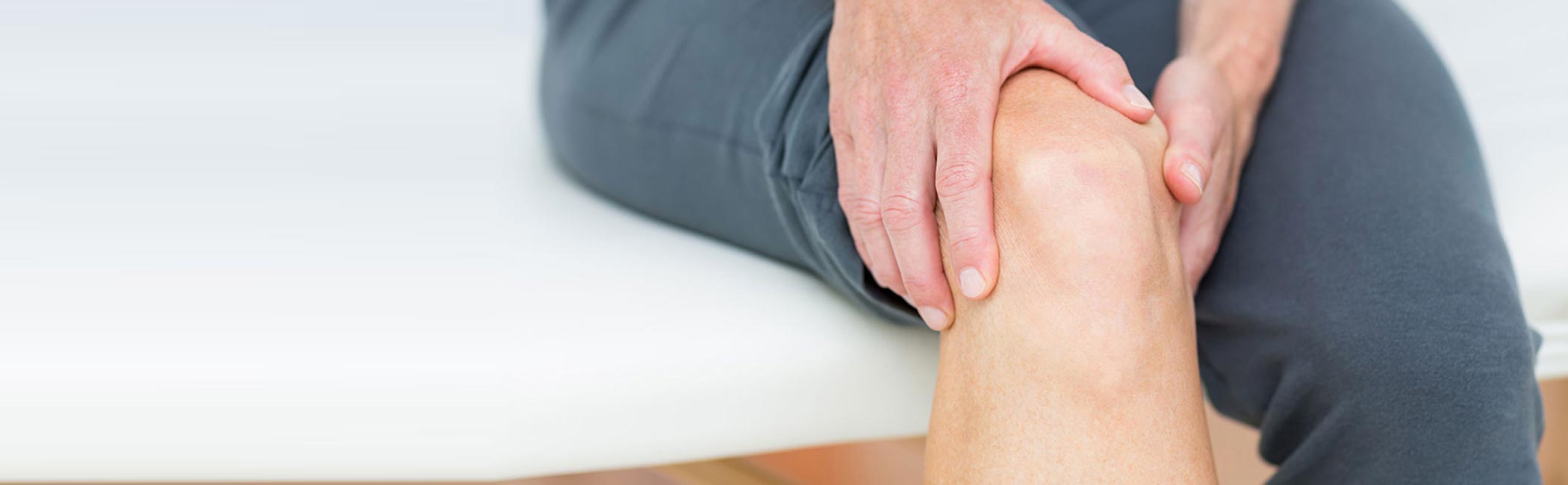 En kvinde holder sig om knæet grundet knæsmerter.