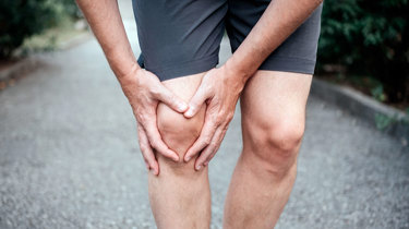 Mand holder sig til knæ, der gør ondt.
