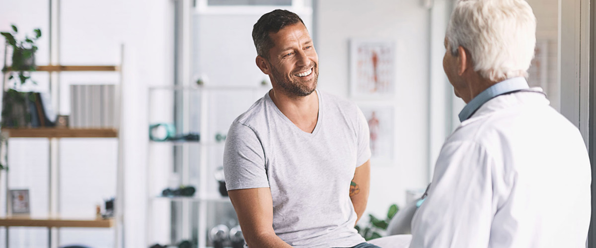 En patient og ortopædkirurg smiler under konsultation.