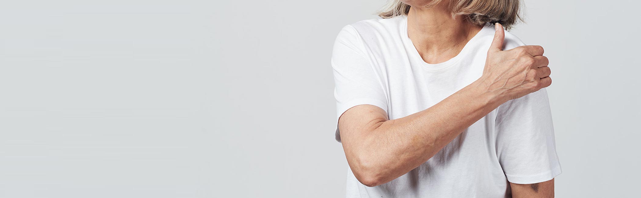 En kvinder tager sig til skulderen grundet skuldersmerter.