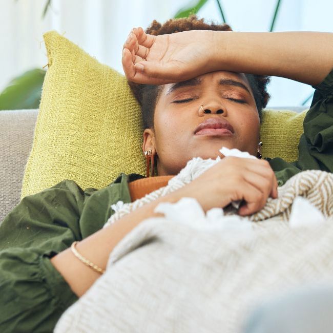 Kvinde ligger i sin sofa og er syg.