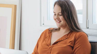 Kvinde sidder ved sin computer og er ved af booke tid til en overvægtsoperation.