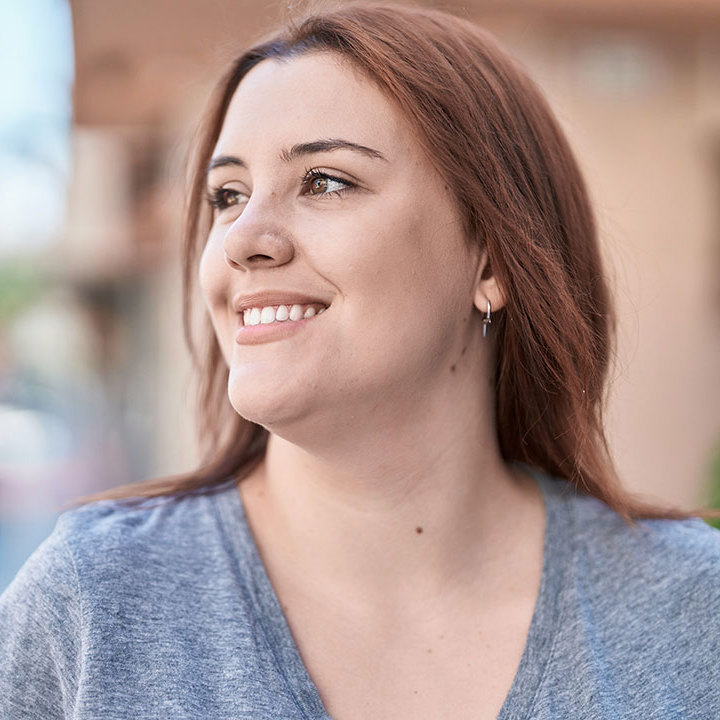 Ung smilende kvinde kommer gående på gaden.