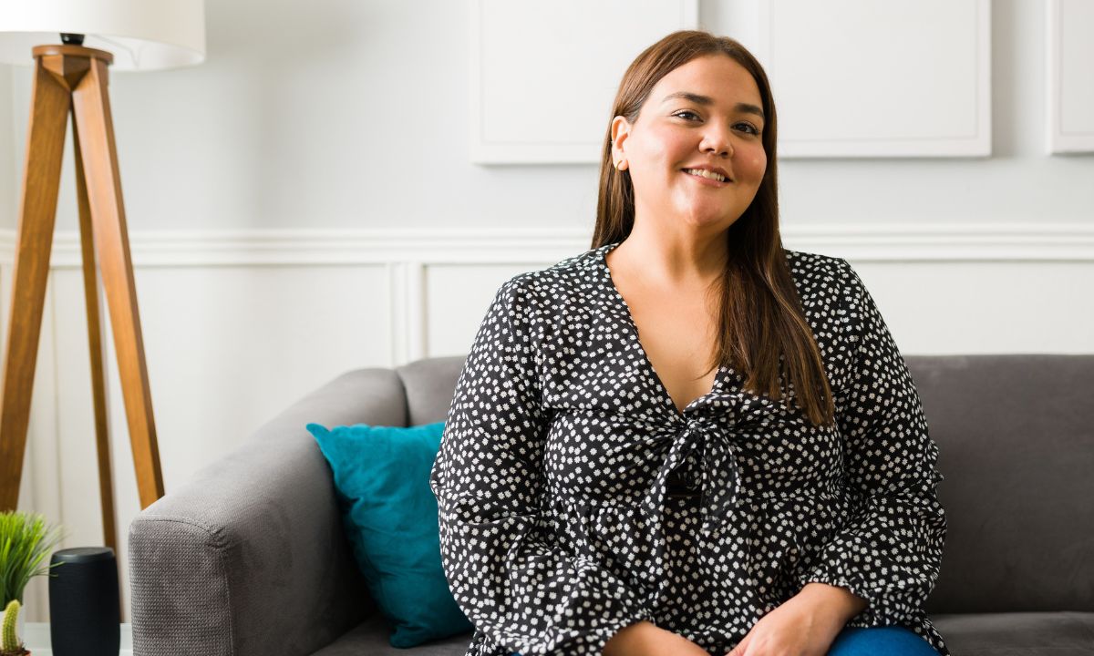 En kvinde sidder og smiler i en sofa.