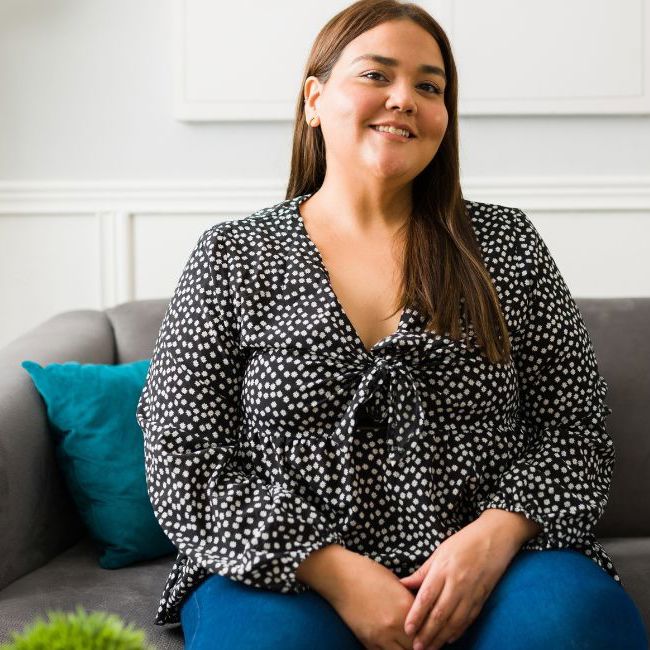 En kvinde sidder og smiler i en sofa.