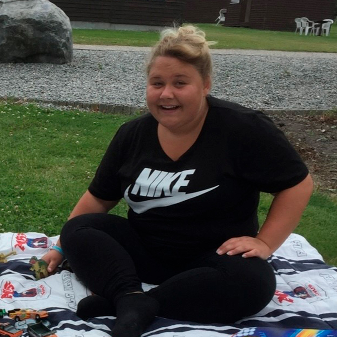 Frederikke på et tæppe i en park smiler til fotografen i perioden før hendes overvægtsoperation