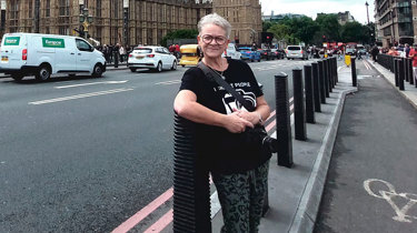 En kvinde står på gaden og smiler.