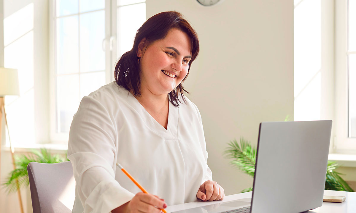 En glad kvinde smiler, fordi hun er blevet henvist til en overvægtsoperation på Aleris.