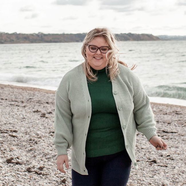 Overvægtig kvinde går på strand.