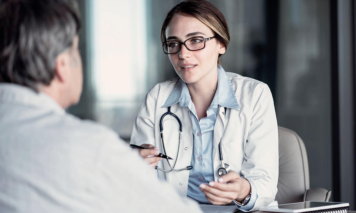 Overvægtig mand sidder og taler med en læge.