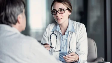 Overvægtig mand sidder og taler med en læge.