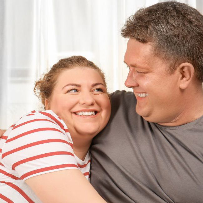 Et glad par krammer i sofaen.