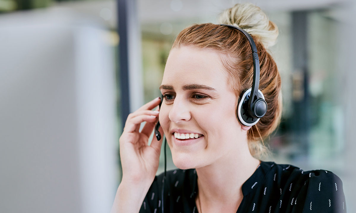 En medarbejder i Aleris kundeservice sidder og taler med en patient i telefon med headset på.
