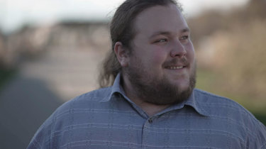 Overvægtig mand går og smiler.