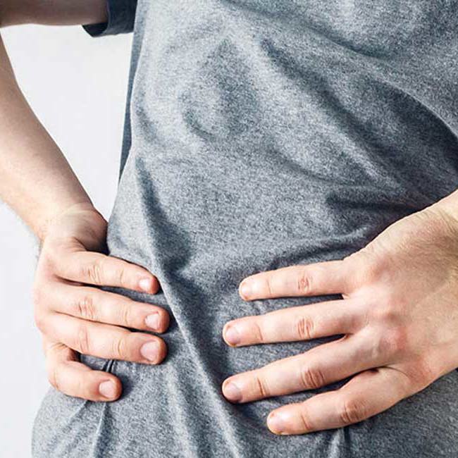 En mand har ondt i ryggen grundet rygsøjlegigt.